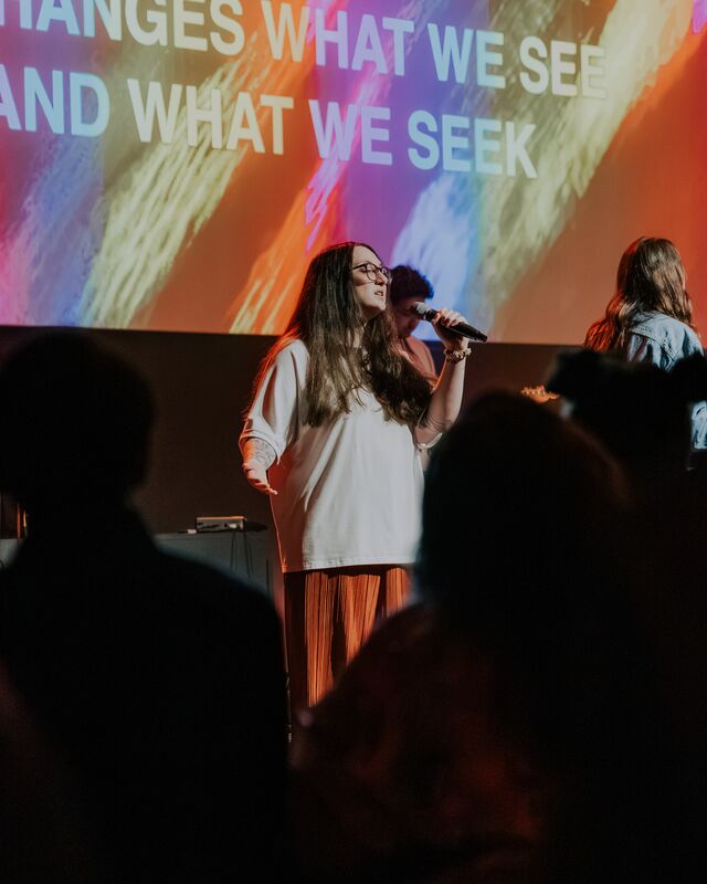 A worship leader singing on stage during a Sunday service
