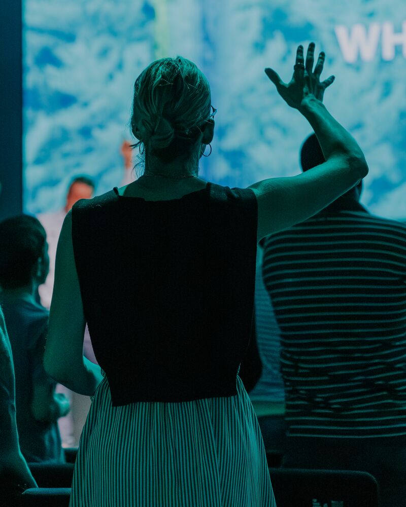 A woman worshipping with hands raised during a Sunday service